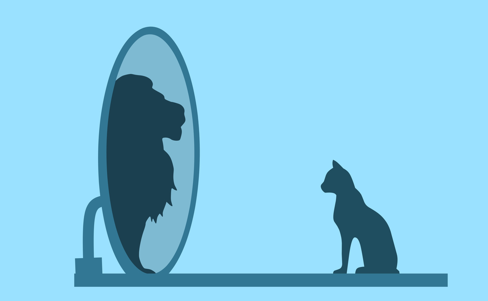 Mit einer stark auf sich selbst fokussierten Perspektive neigen Narzissten dazu, die Sichtweisen anderer Menschen komplett auszublenden. Die Illustration zeigt eine Katze die in den Spiegel schaut und einen Löwen sieht.